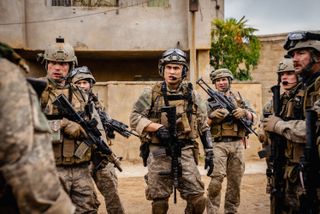 A group of soldiers standing in full gear with weapons.