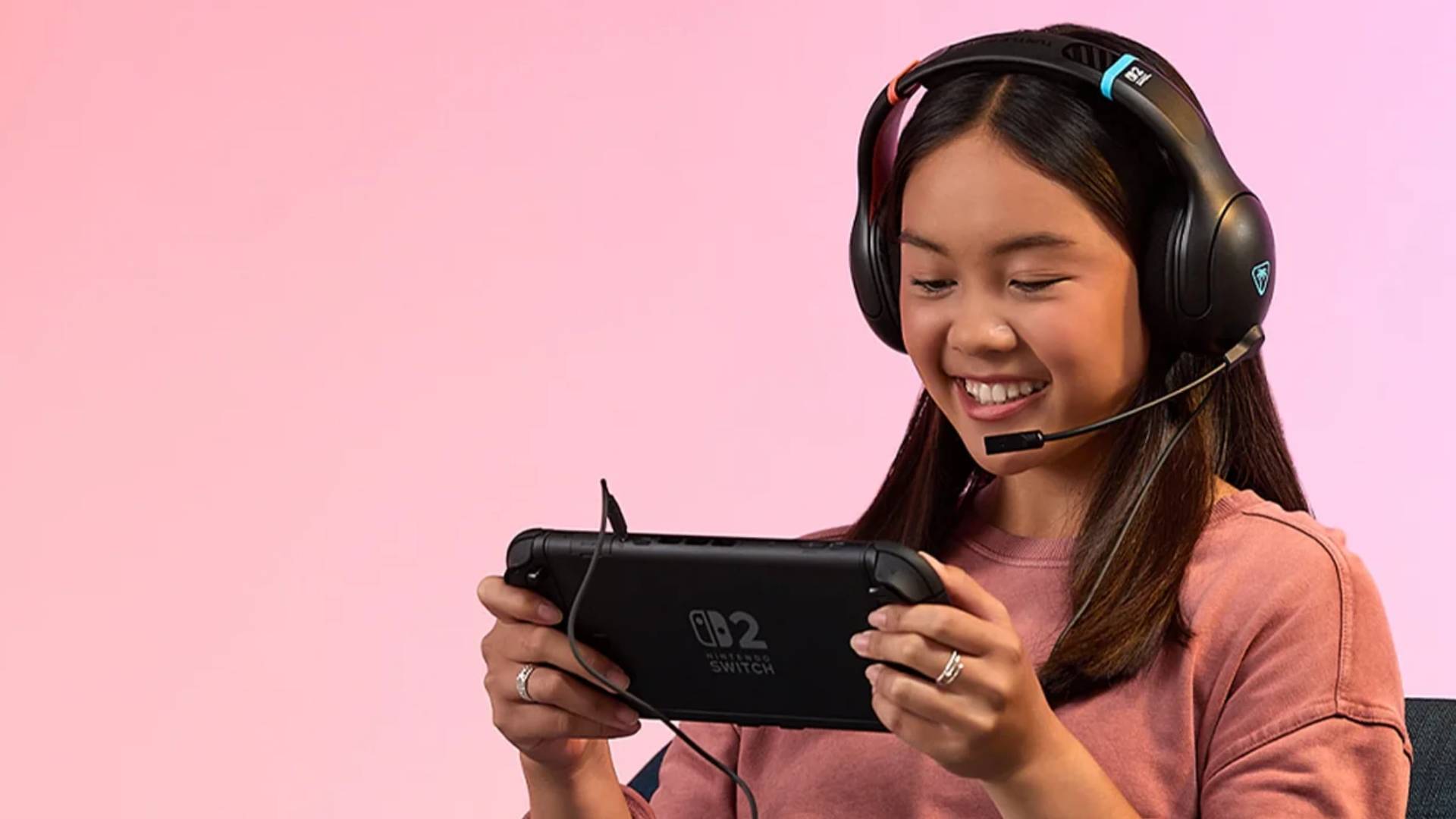 Official promo image of a person with the Turtle Beach Airlite Fit wired headset on their head, looking down at a Nintendo Switch 2.