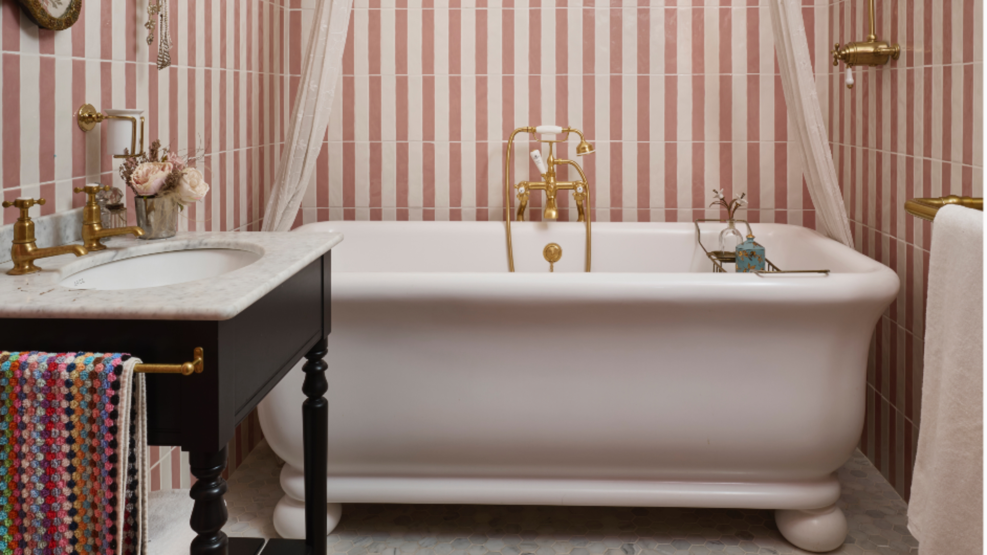 Pearl Lowe's vintage style bathroom with classic bath, pink and white tiles, washstand, patterned towel, brassware