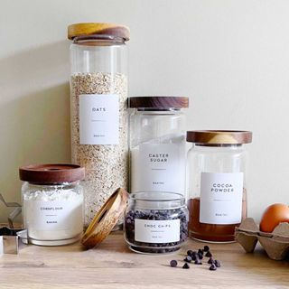 glass storage jars with wooden lids and labels to show how to organise a kitchen in style