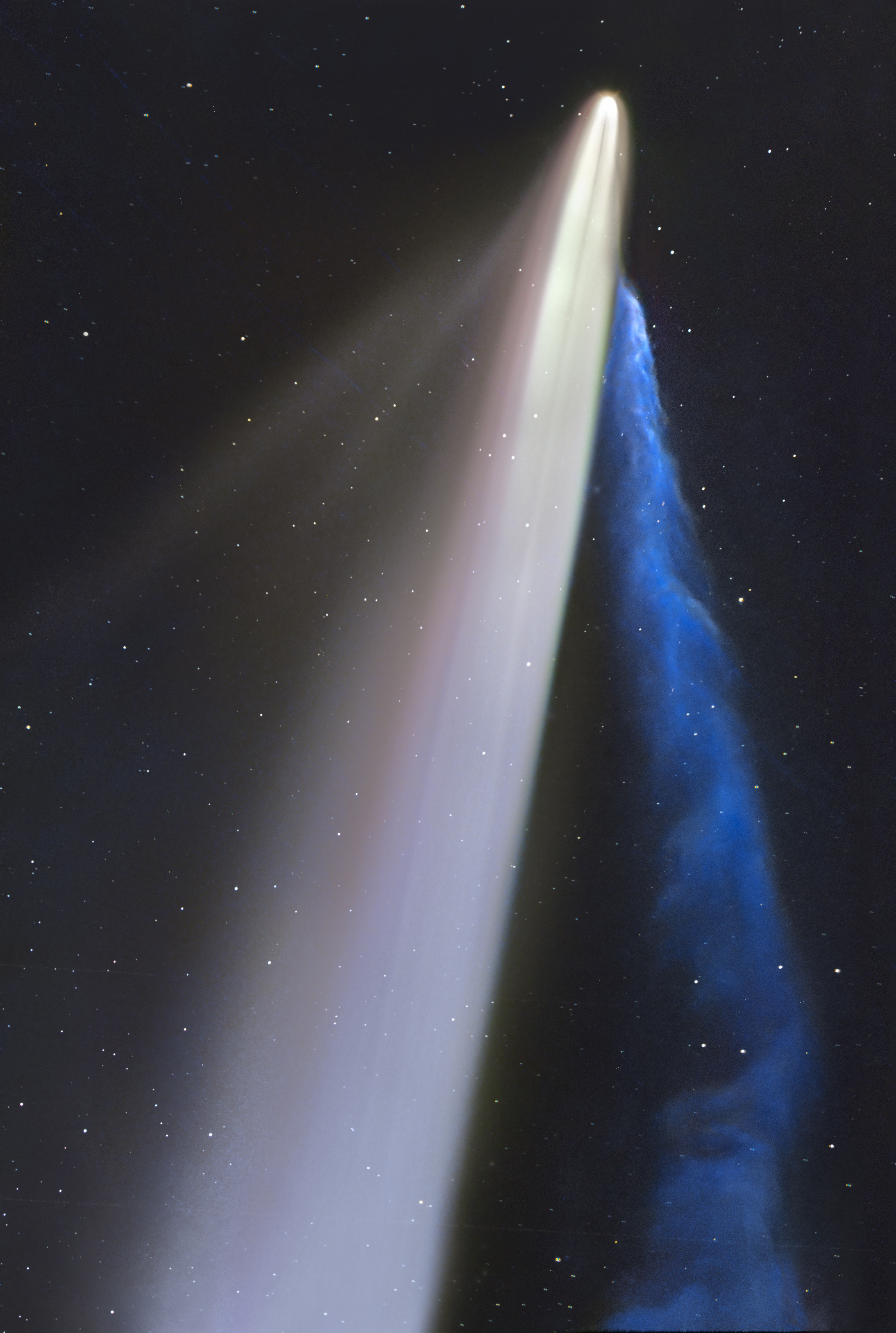 A large comet streaks across the darkness of space, with a corresponding blue smoky plume next to it