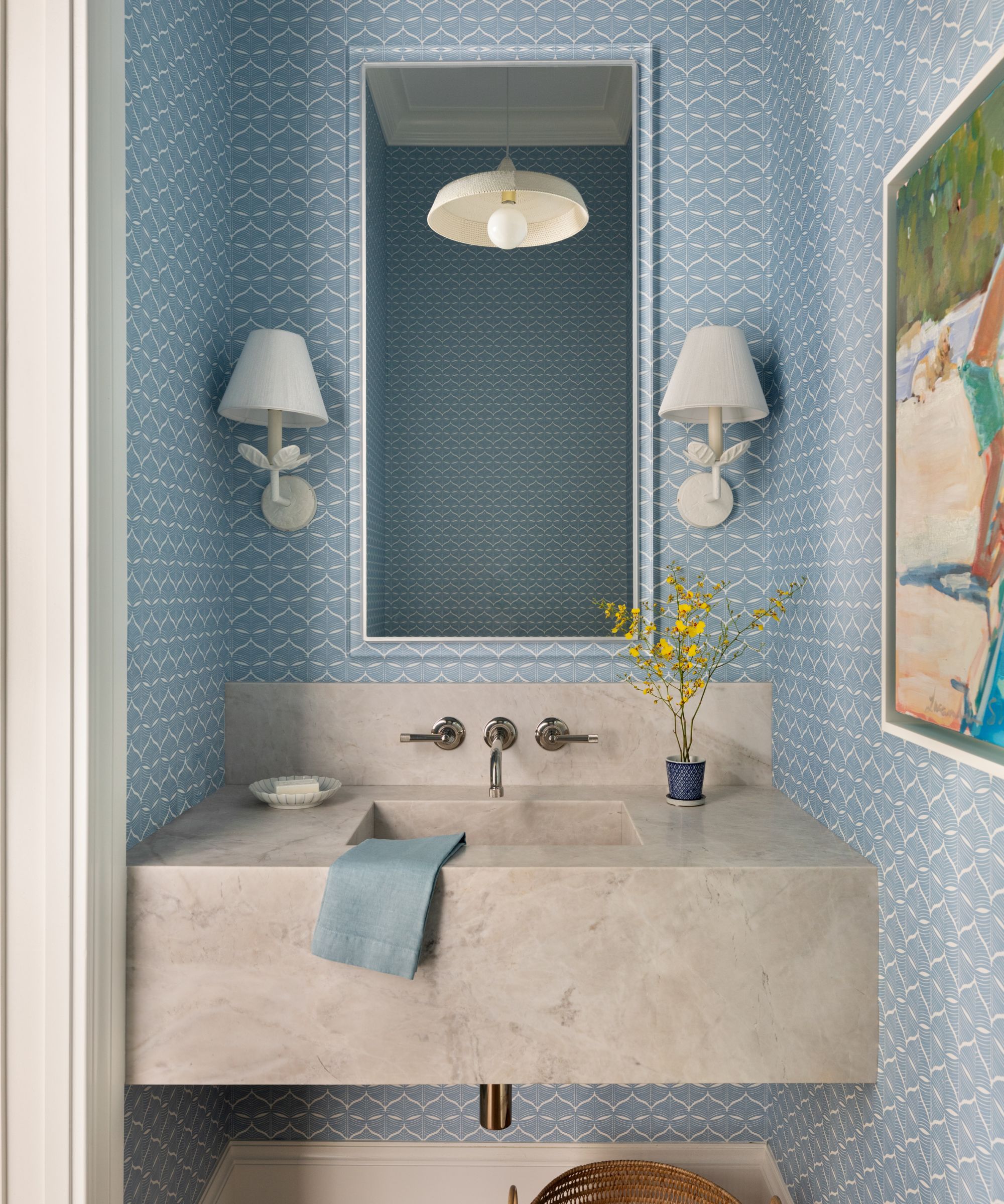 A blue powder room with a floating stone vanity with brass hardware
