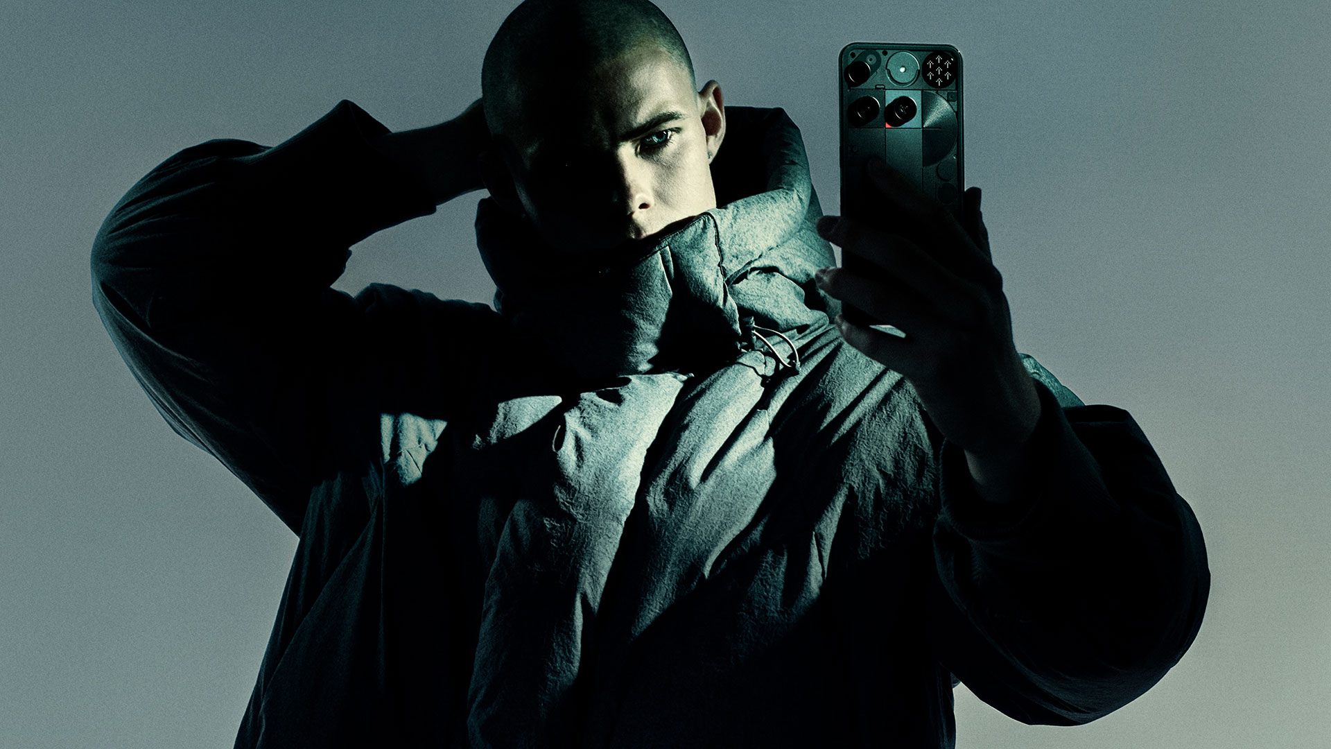 Man in winter jacket holding up the Nothing Phone 3 to take a selfie