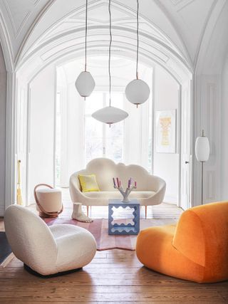 A white living room with a white and orange couch and a pink carpet