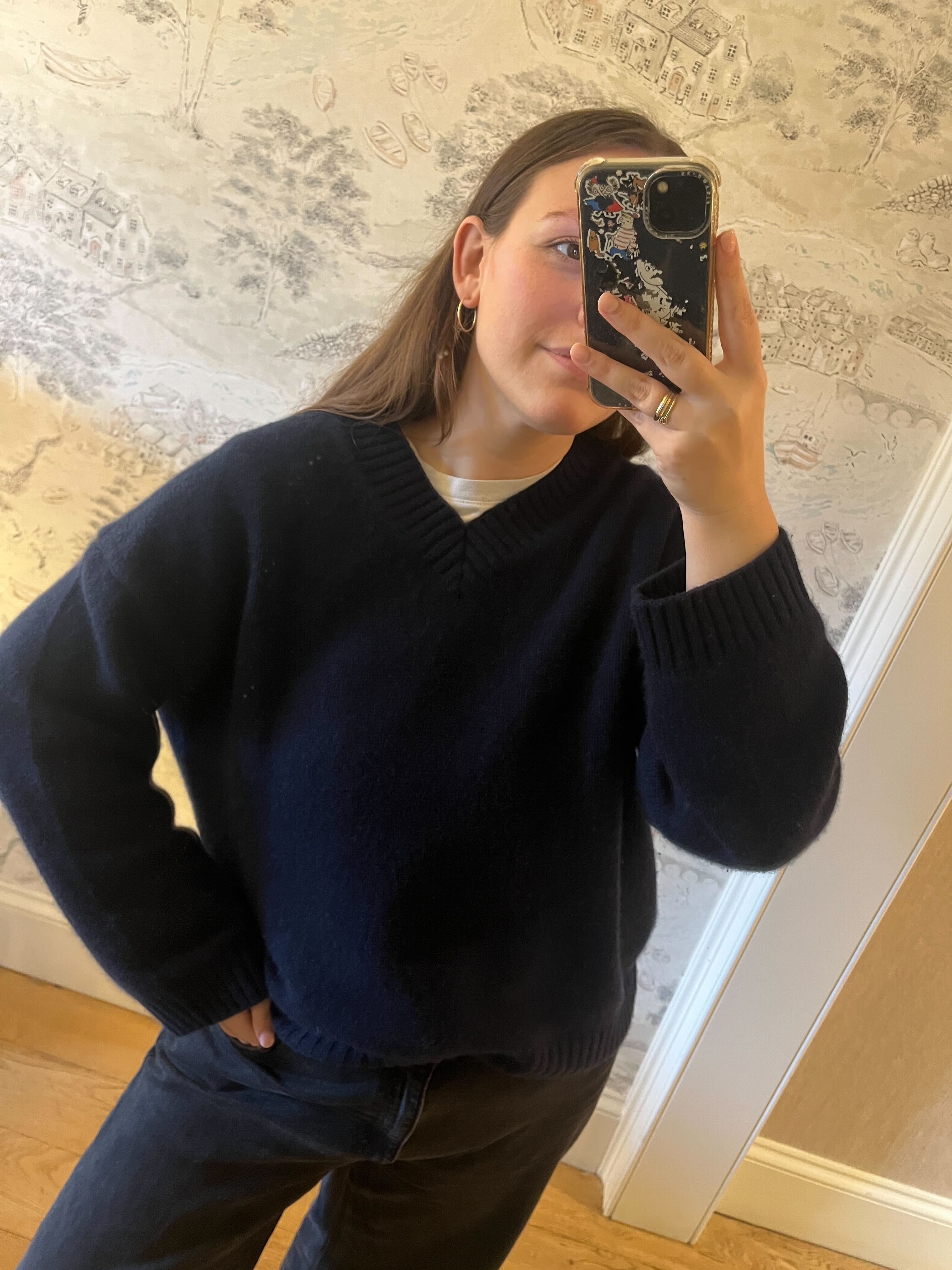 Who What Wear Managing Editor Poppy Nash wears a navy v-neck jumper and with black jeans.