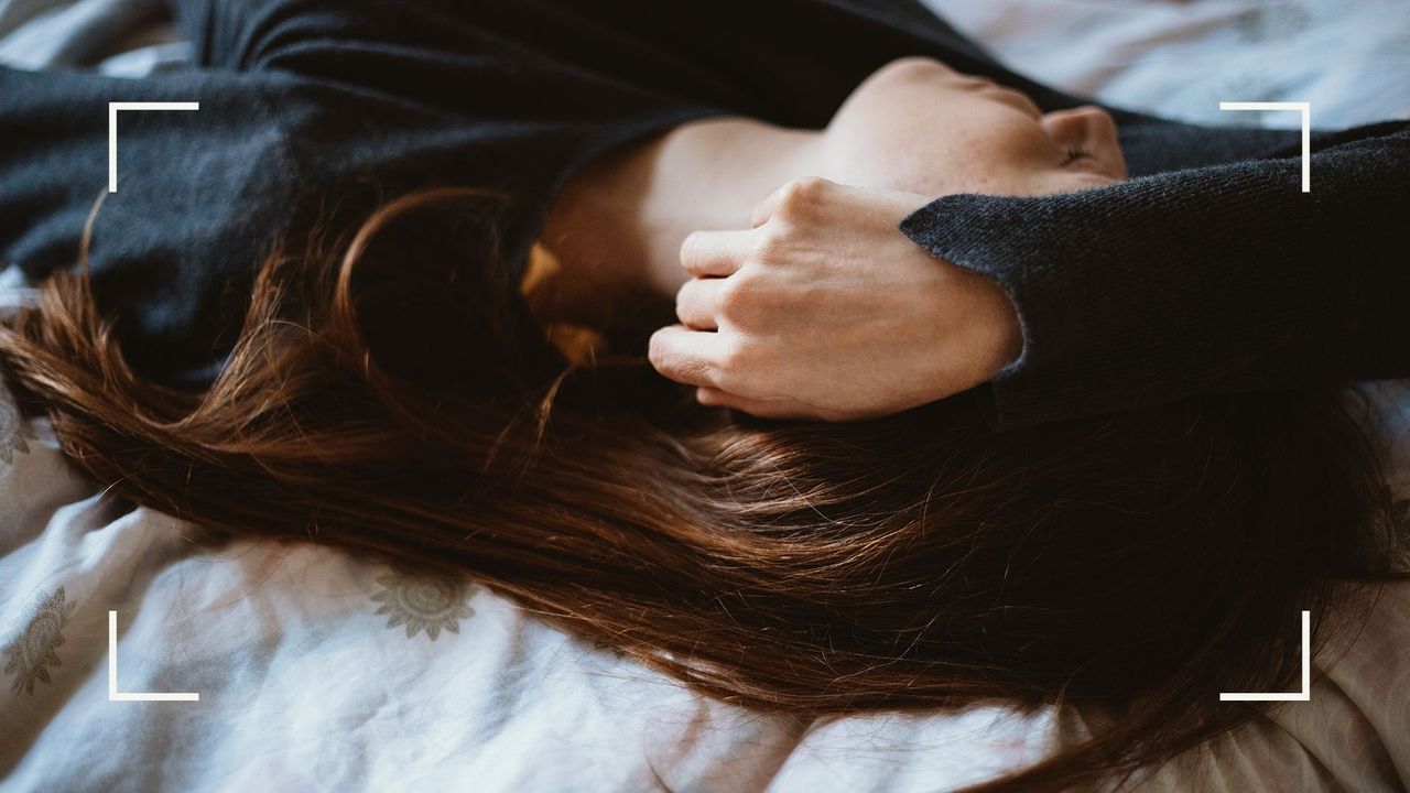 Woman lying down on the bed over white bed sheets, struggling to sleep at night