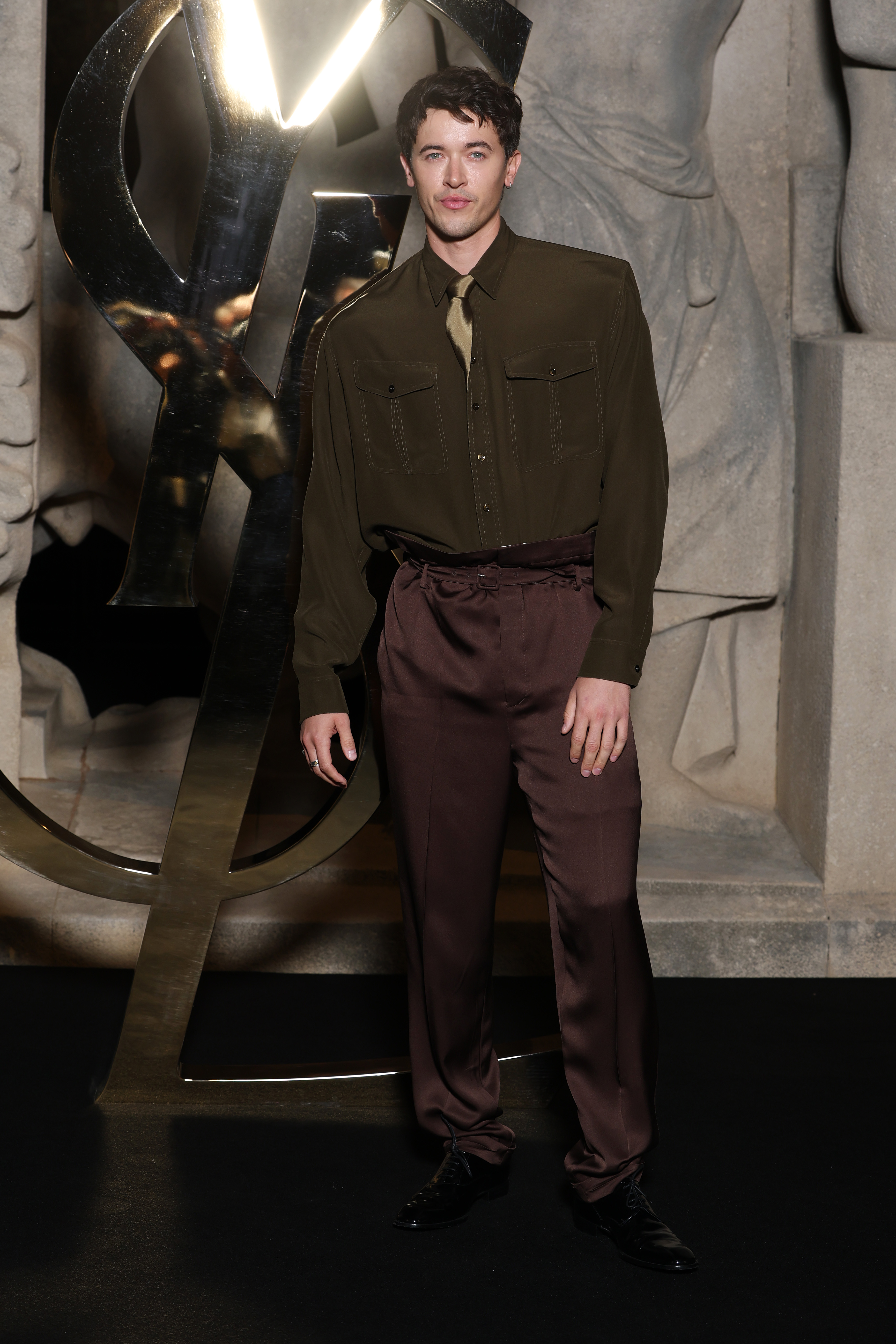 tom blyth wearing a green shirt and brown trousers at saint laurent