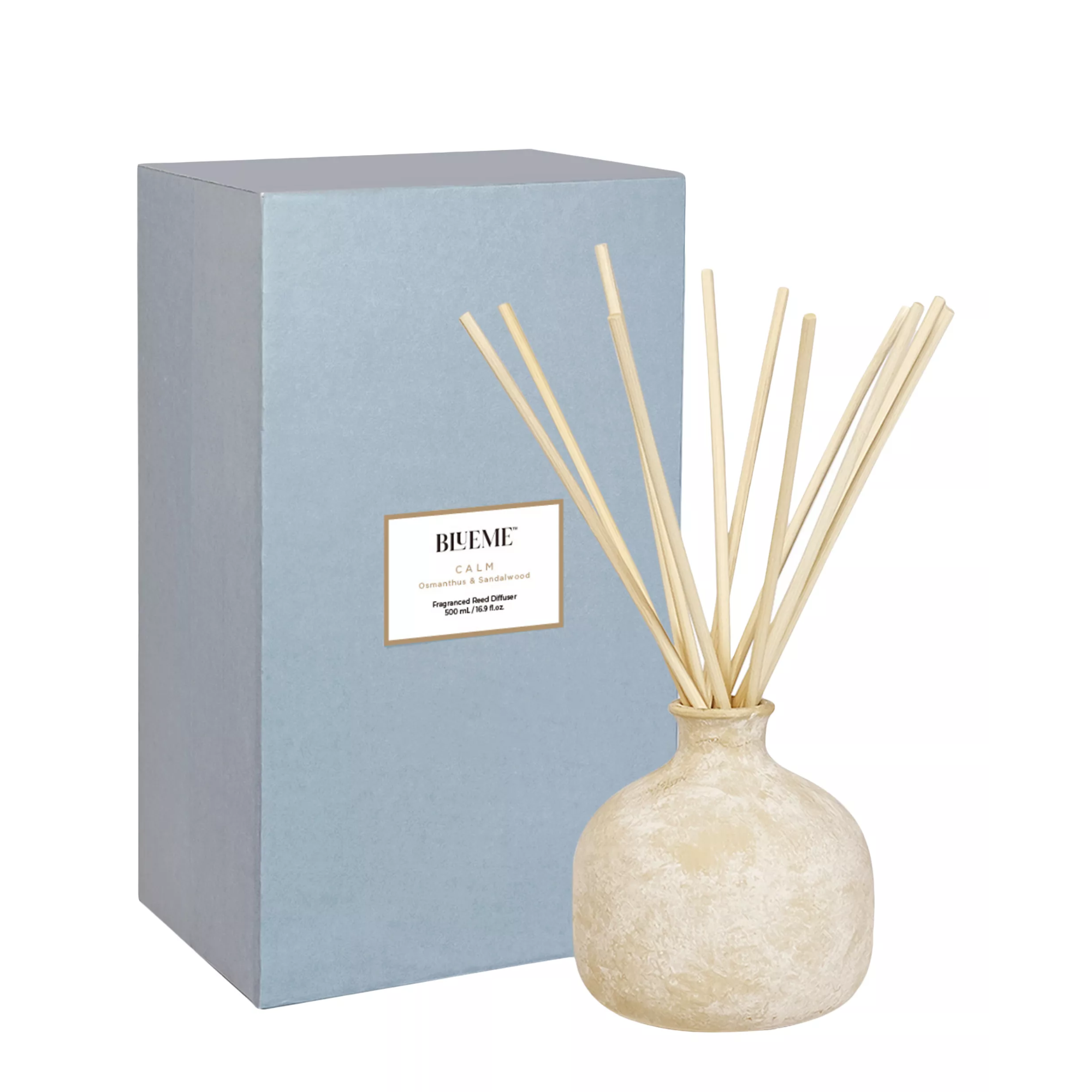 ceramic vessel holding reed diffuser sticks next to a blue box