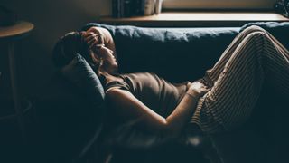 Woman lying down on sofa napping