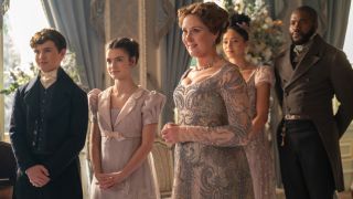 (L to R) Will Tilston as Gregory Bridgerton, Florence Hunt as Hyacinth Bridgerton, Ruth Gemmell as Lady Violet Bridgerton, Emma Naomi as Alice Mondrich, Martins Imhangbe as Will Mondrich standing together.