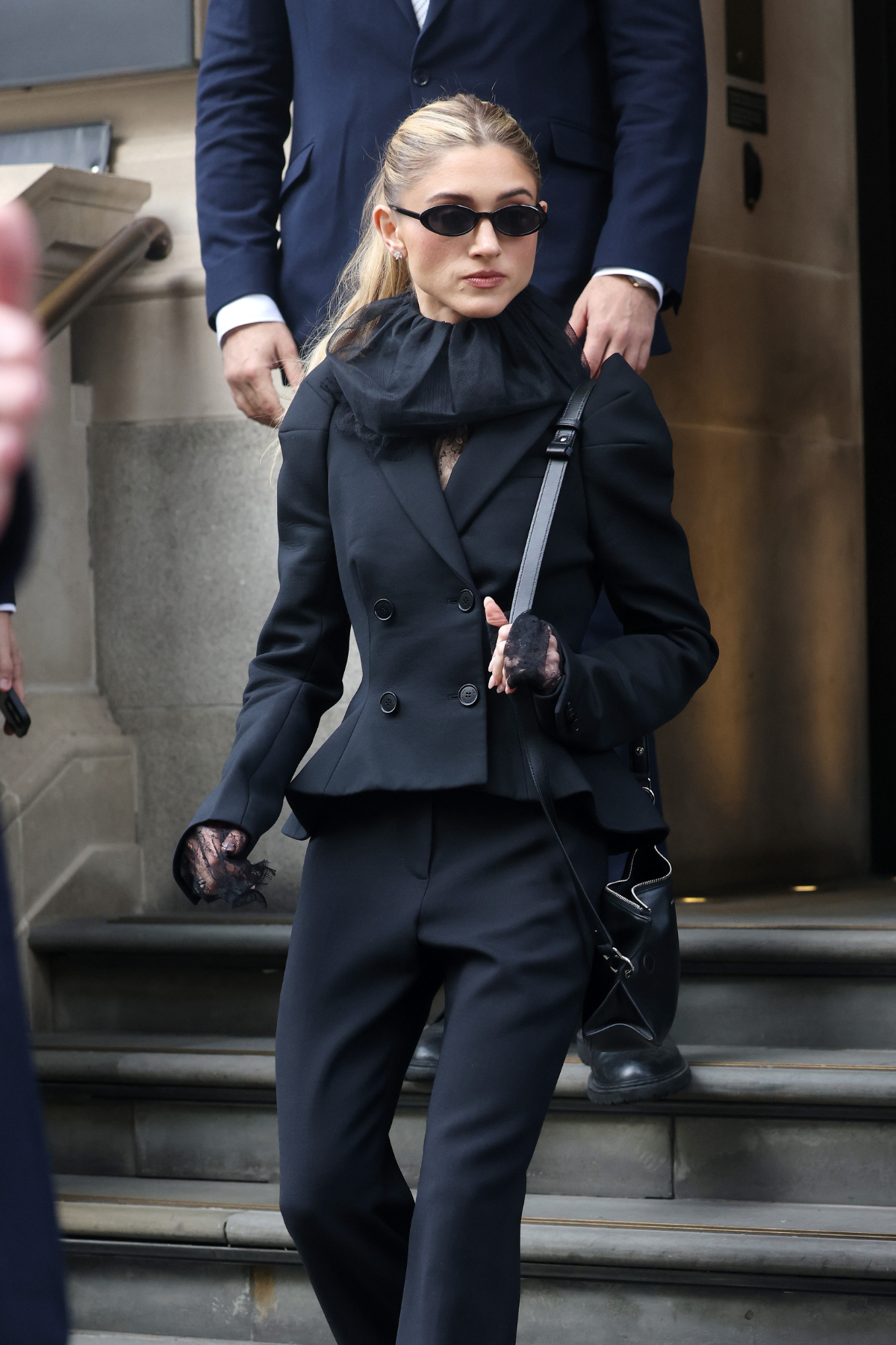 a blonde woman with a black outfit and dark sunglasses