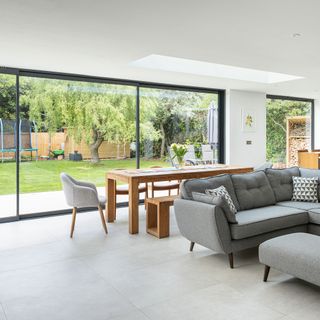 Open plan living and dining room with floor-to-ceiling glass sliding doors leading to garden