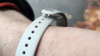 The Xiaomi Smart Band 9 on a man's wrist in front of a green park.