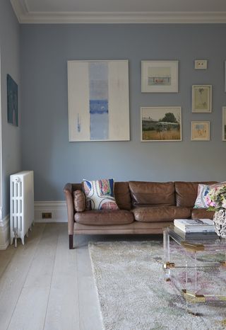 blue walls on a transitional-style living room with leather sofa and pillows