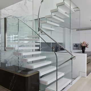 Bisca open staircase in a white modern home with a white kitchen beyond