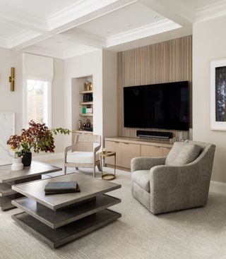 media/living room with tv, two coffee tables, armchairs, bookcase, tv mounted on paneling