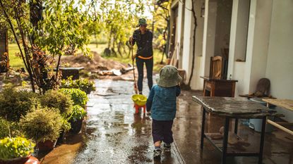 A woman and her child sweep up after a flood.