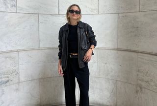 Woman wearing a leather jacket, a black top, and black trousers.