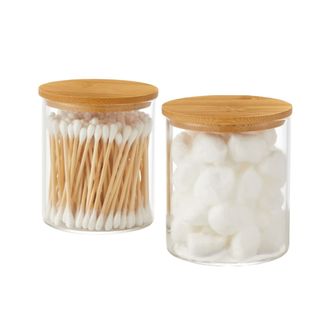 Two glass jars with bamboo lids containing cotton buds and cotton balls