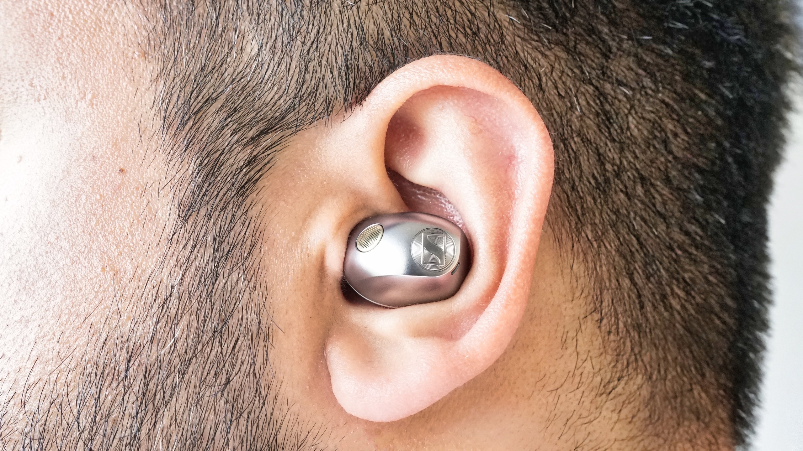 Sennheiser Momentum True Wireless 5 in white, showing details of the buds held in a hand