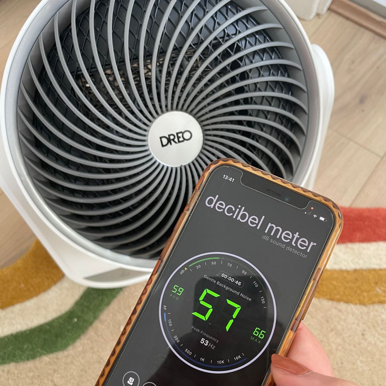 Hand holding a phone in front of the Dreo Smart Whole Room Heater 714S