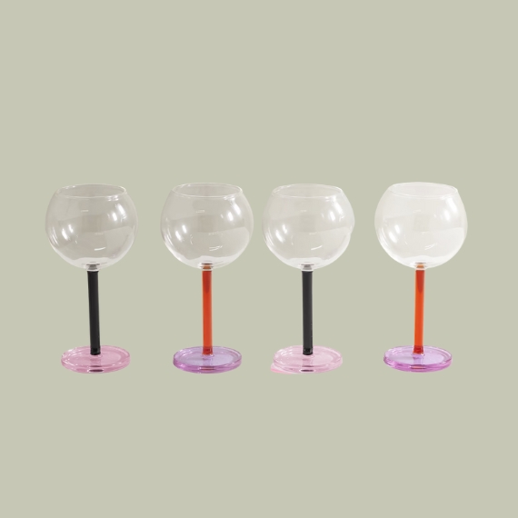 A series of four wine glasses with colorful pink, red, and green stems sits against a pale green background.