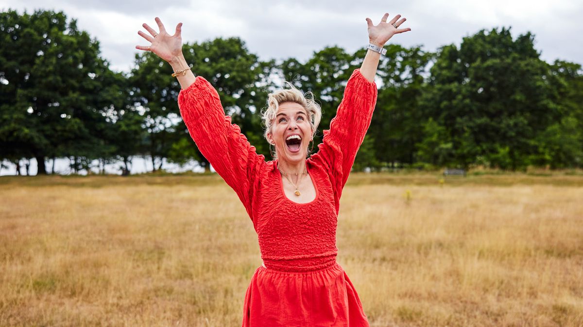 Vicky McClure wears a red dress and cheers in a field