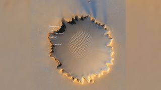 Large crater with a tiny black speck in top left corner on the rim labeled as Opportunity.