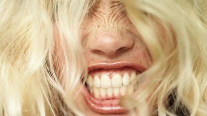 a blonde person showing their teeth