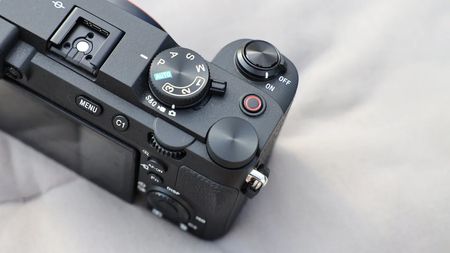 Close-up of a black digital camera's top controls including mode dial, shutter button, on/off switch, and menu buttons
