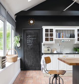 kitchen with black slate wall and white cabinets with blackboard on wall