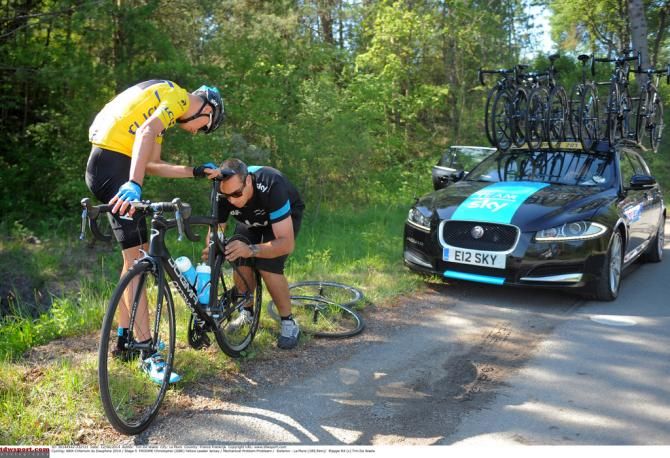 Froome checks his rear wheel after puncturing