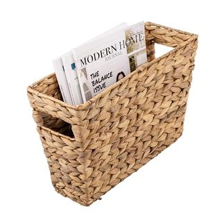 A narrow, tall woven storage basket for magazines on a white background