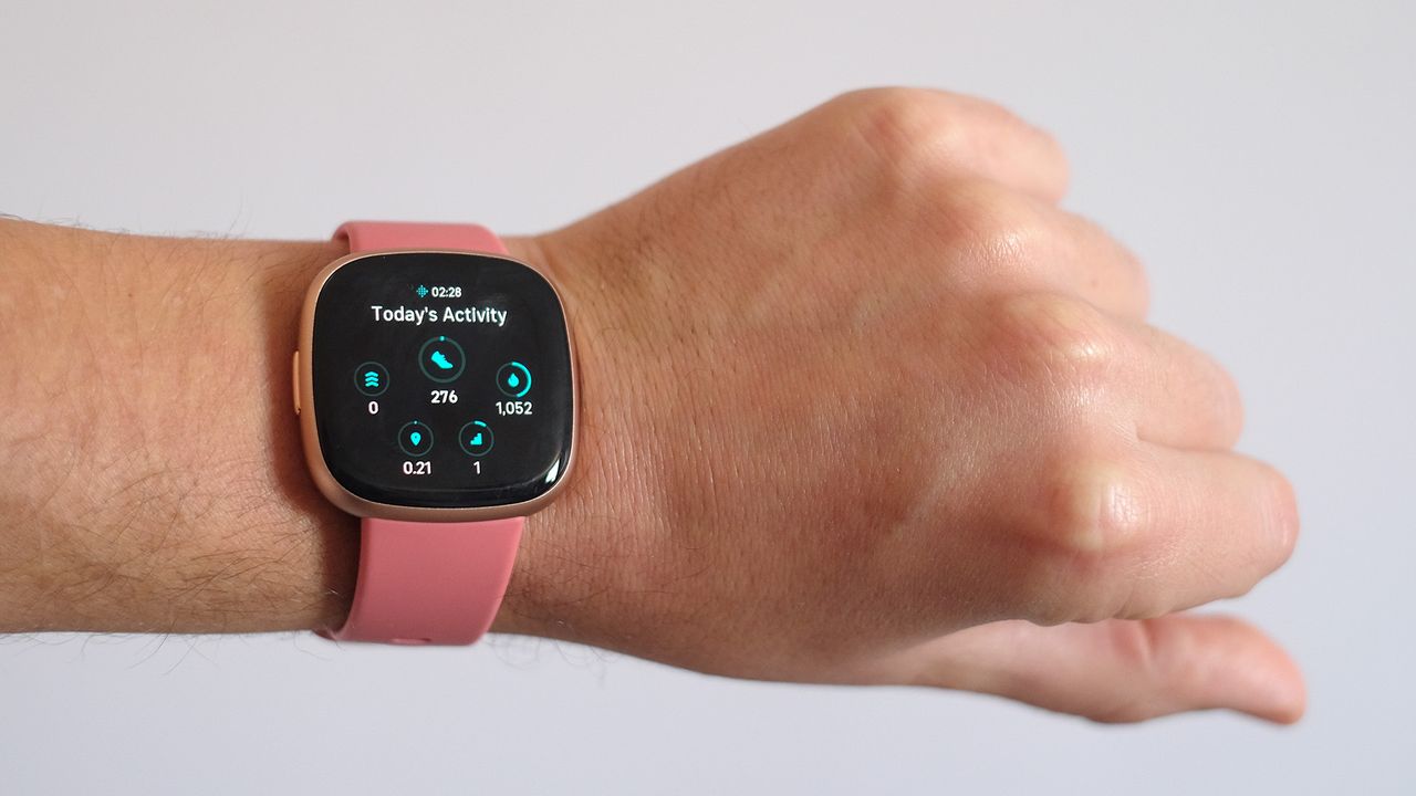 Fitbit Versa 4 being worn on a wrist with white background.