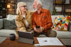 Senior happy couple do contactless payment and control bills on tablet