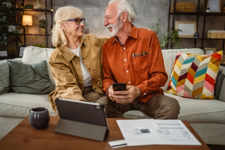 Senior happy couple do contactless payment and control bills on tablet