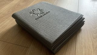 Primasole yoga mat folded on a wooden floor