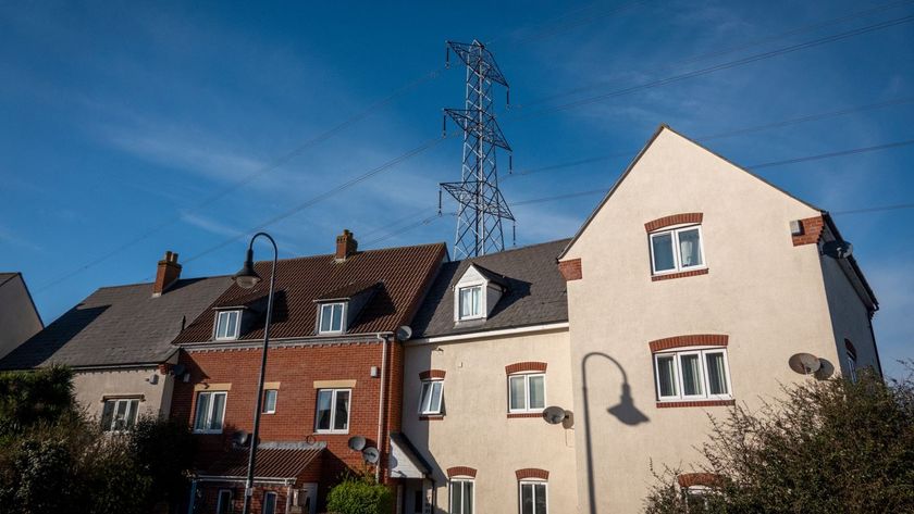 A row of homes with an electricity pylon towering up over the top of them