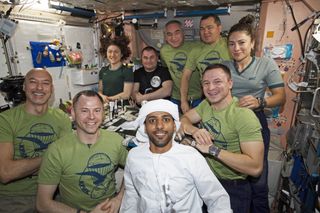 United Arab Emirates astronaut Hazzaa Ali Almansoori, clad in traditional garb, poses for a crew photo aboard the International Space Station with his crewmates on Oct. 1, 2019.