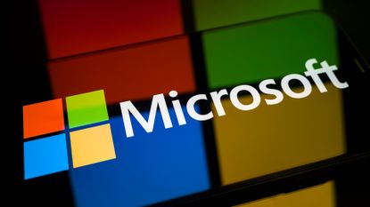 Microsoft logo and branding pictured against a reflective background with multi-colored square logo reflecting.