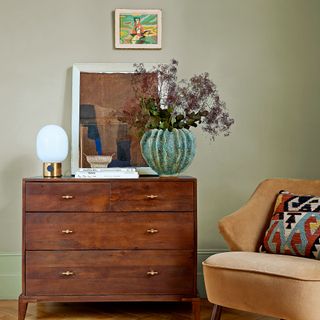 Green walls with brown chest of drawers and yellow chair