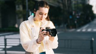 A woman holding the Sony ZV-E10 camera