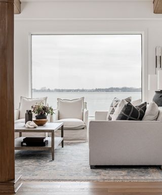 A white and blue living room with a large window view of a lake