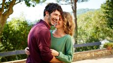 Man and woman happy and smiling together standing outdoors among trees, hugging and close to each other, representing how often you should you have sex