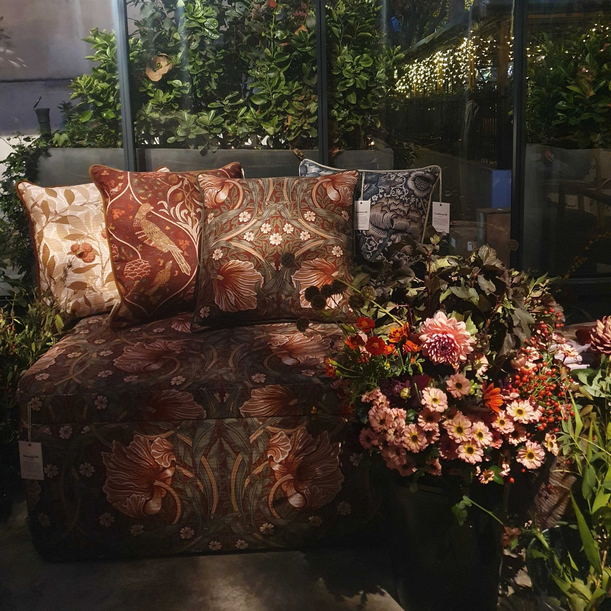 The Swyft x Morris &amp;amp; Co press event, showing flowers, cushion and ottoman.