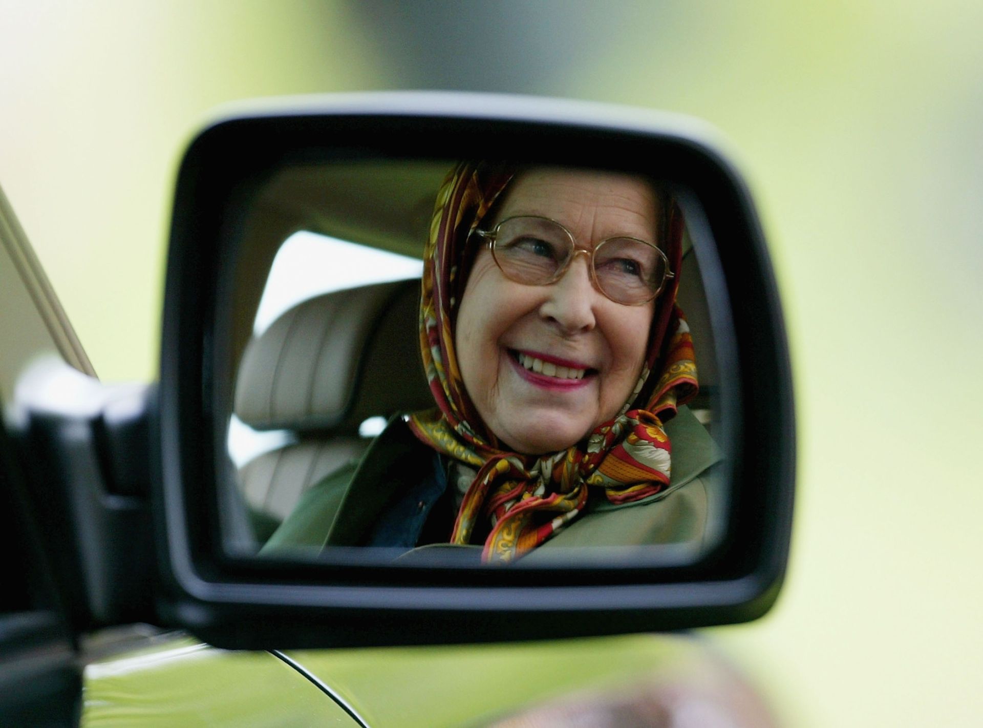Queen Elizabeth's reflection in a side-view mirror of a car