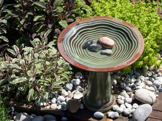 ceramic bird bath with stones in the basin