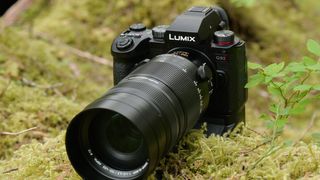 Panasonic Lumix G9 II camera on mossy ground with vertical grip accessory attached