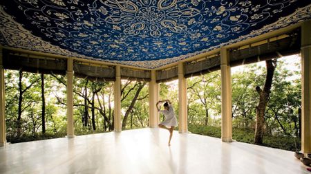 A woman does a yoga pose inside an outdoor pavilion at the Ananda in the Himalayas