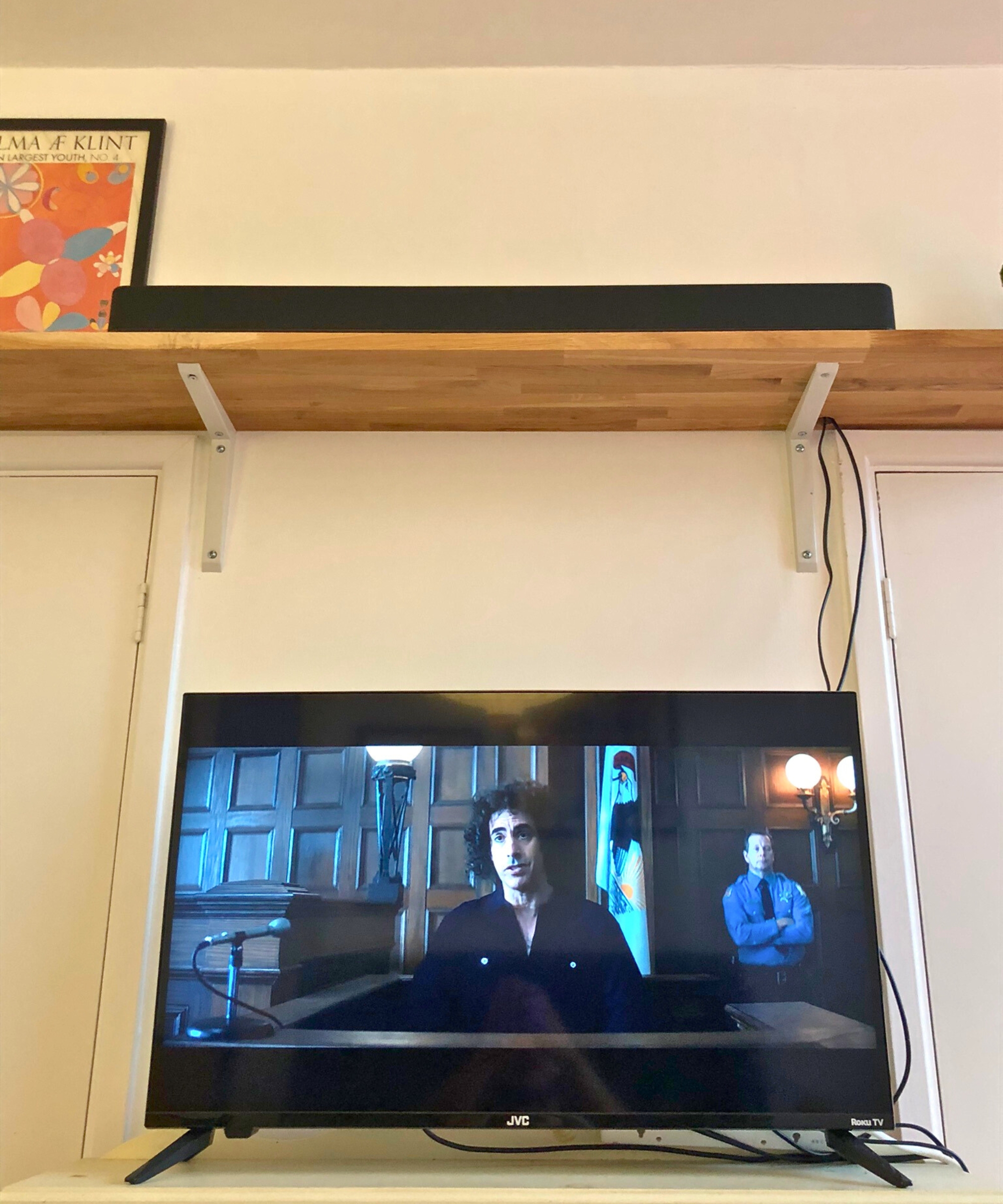 TV showing Trial of the Chicago 7 with Fire TV Soundbar Plus above on wooden shelf, in Dan Fauzi's home.